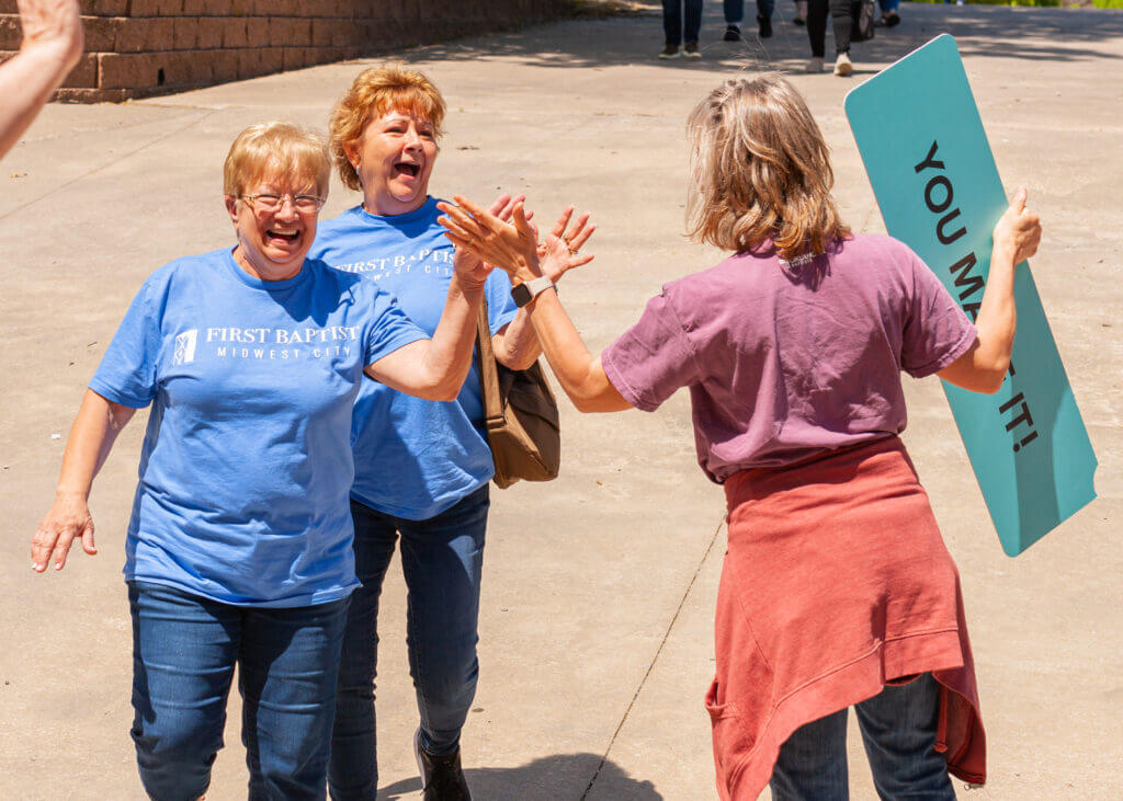 Two women high five another one after doing mission work together