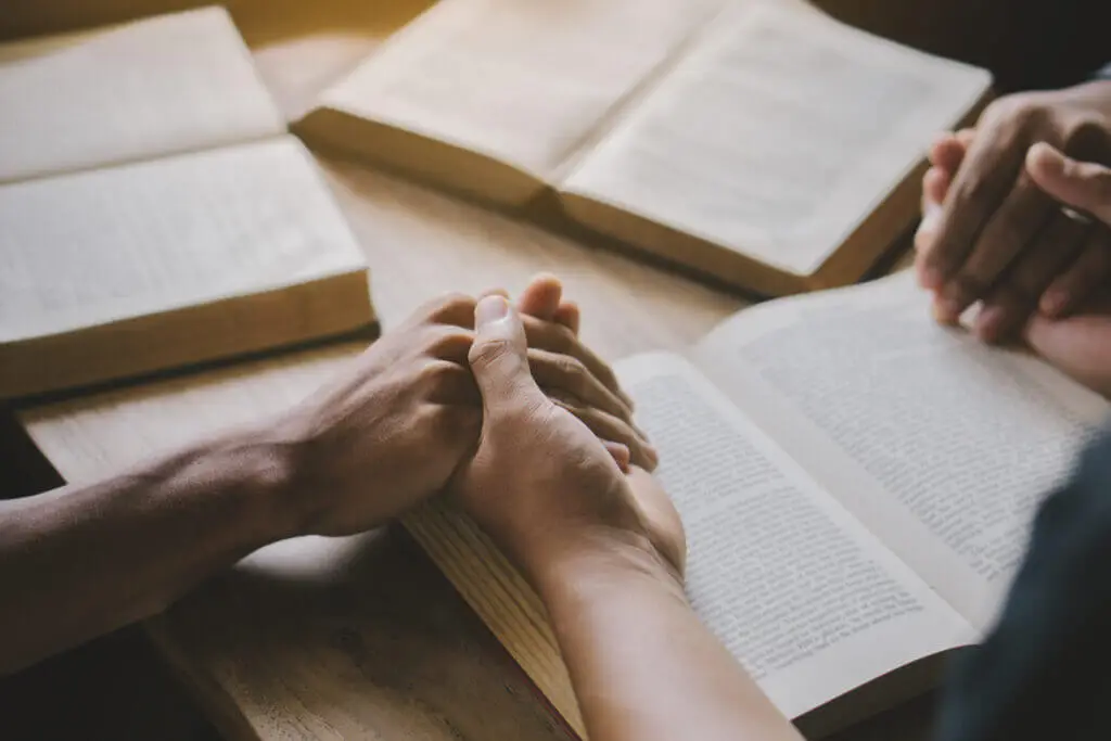 Group of christian people reading and study bible in home and praying together.